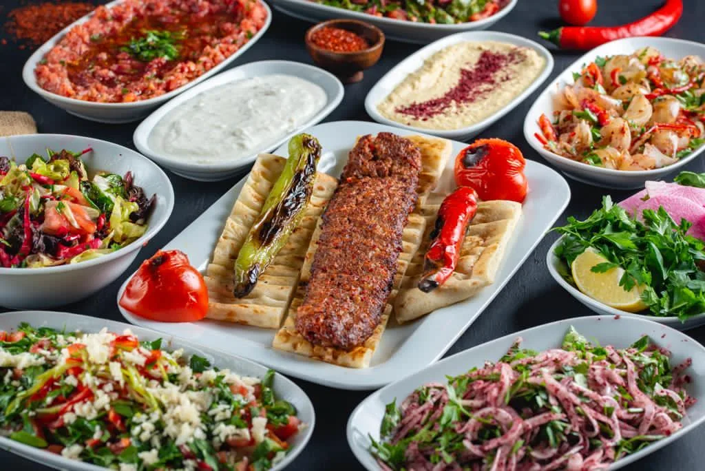 Adana kebabı, köz biber ve sofrayı dolduran mezeler